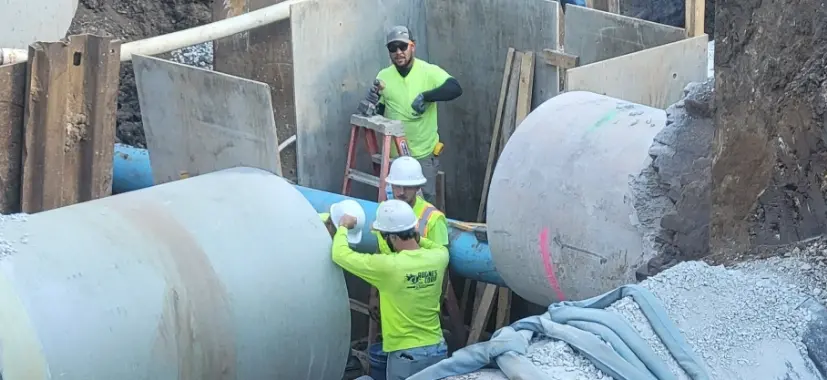 Two men in neon yellow shirts working on a deep sewer line