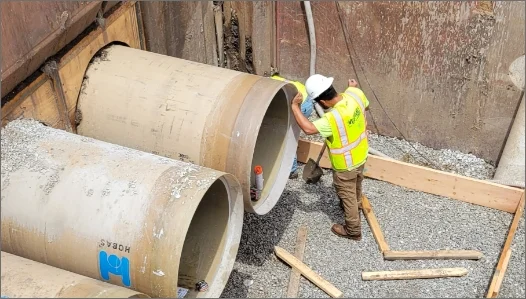 Man standing next to large concrete pipe working
