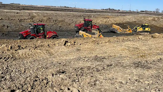 Three large construction vehicles leveling out a path on dirt pile